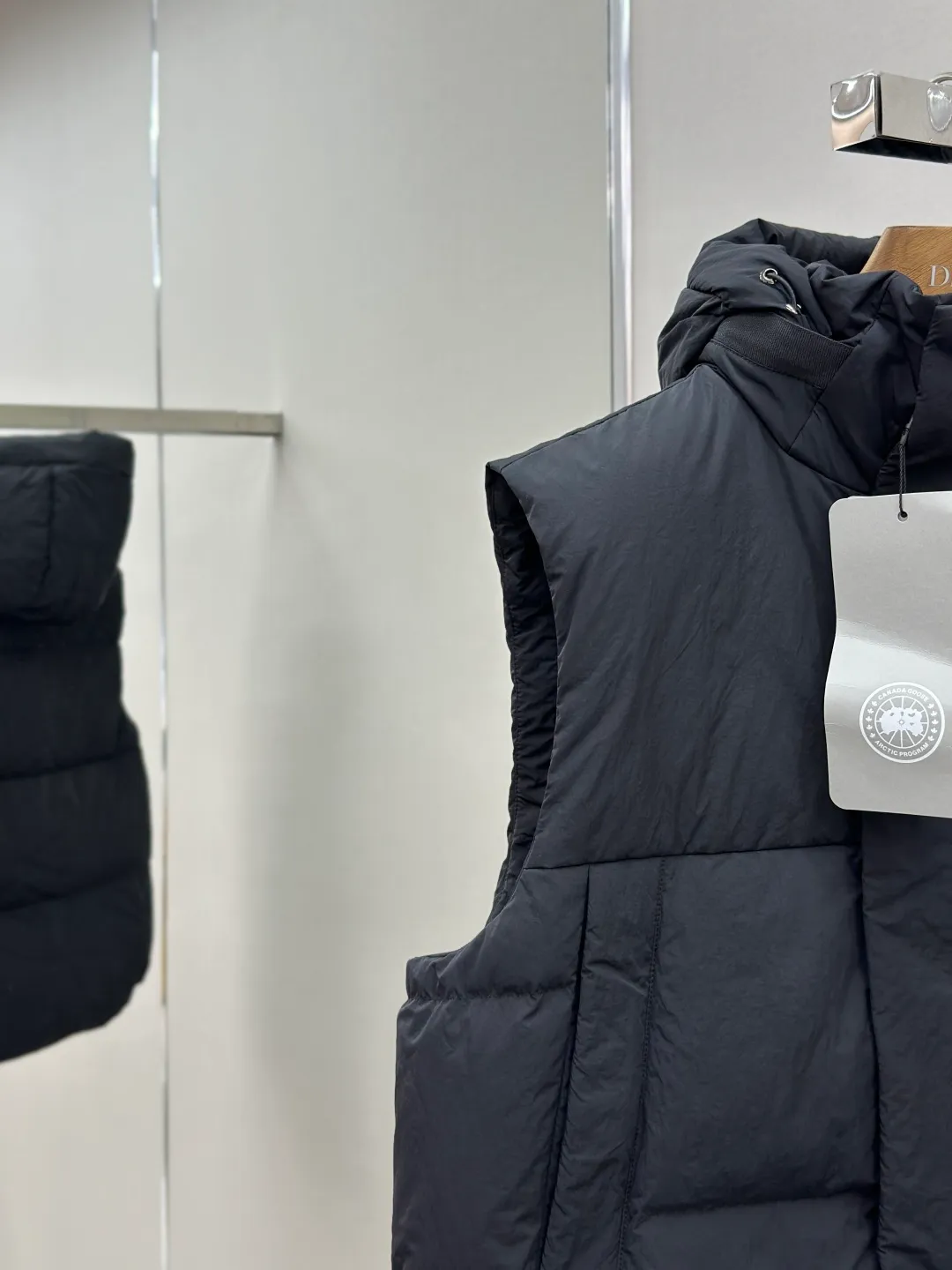 P760 Canada Goose logo hooded down vest Fabric selection: The use of high-quality protective nylon fabric not only enhances the wear resistance of the surface, but also takes into account wind resistance, ensuring excellent performance in various harsh weather conditions.  90 national standard high-quality white duck down: selected high-loft down, weighing 170g, light and warm, with excellent temperature locking performance and good resilience.  Three-dimensional quilting process: Precision thread reinforcement to prevent velvet drilling and ensure that the fluffy and resilient elasticity lasts as new.  Details: Use polyester as the base for woven webbing, and use high-precision computer embroidery to decorate the brand letters on the webbing. The edges of the pattern are clear, the stitches are fine and even, and multiple layers of embroidery threads are stacked to enhance the three-dimensional effect. Accessories: Customized logo Customized zipper pendant Customized hem elastic buckle Customized snap button SIZE: S M L XL